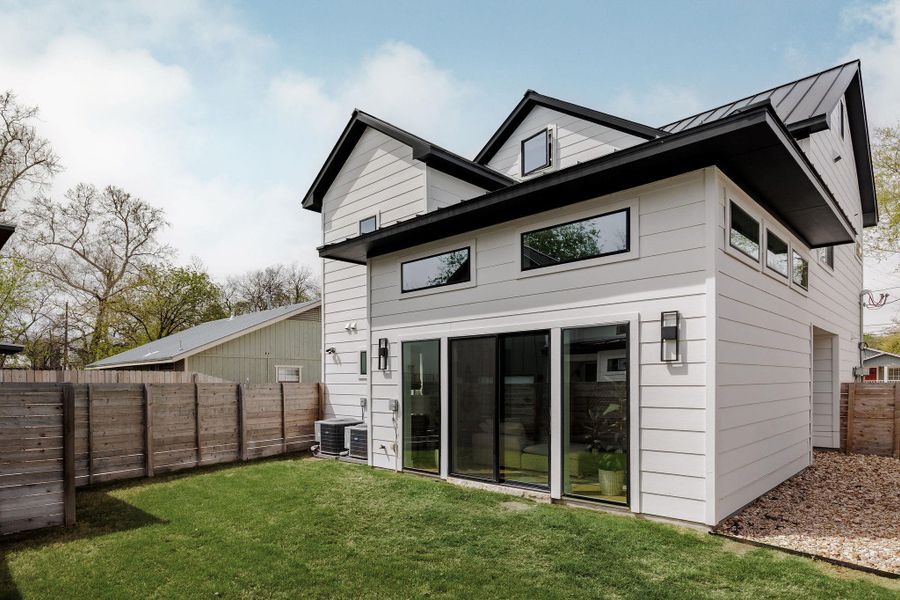 Rear view of house with a fenced backyard and a standing seam roof