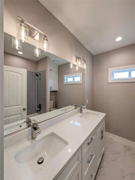 Hall bath with quartz countertops & single handle waterfall faucets
