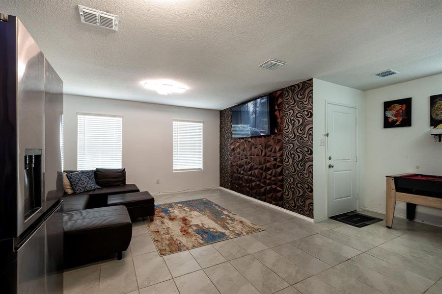 Living room featuring a textured ceiling and light tile patterned floors