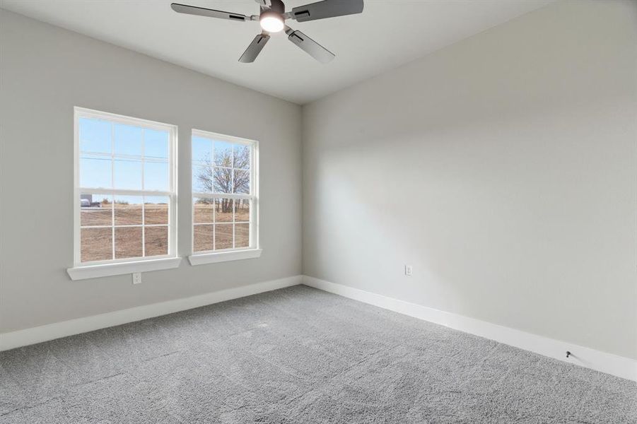 Carpeted spare room featuring baseboards and a ceiling fan
