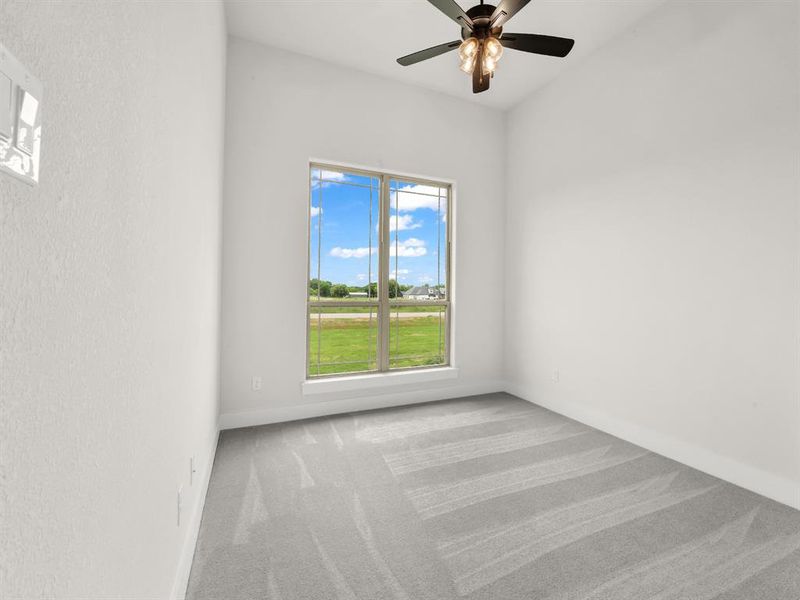 Carpeted spare room featuring baseboards and ceiling fan