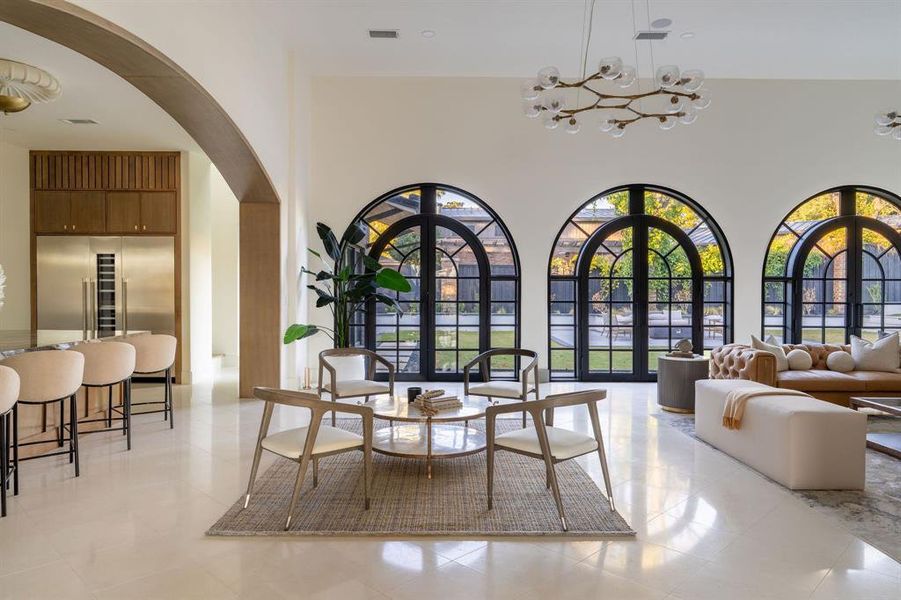 Dining area with arched walkways, a chandelier, a towering ceiling, and light tile patterned floors