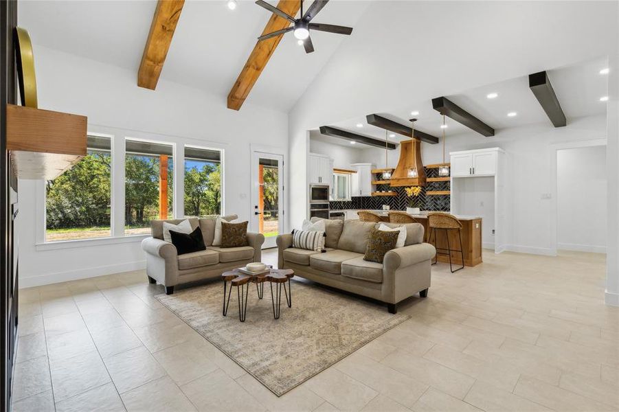 Tiled living room featuring beamed ceiling, ceiling fan, and high vaulted ceiling