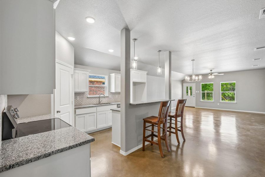 A well-lit, open-concept space features a contemporary kitchen and inviting living area with warm flooring. A well-lit, open-concept space features a contemporary kitchen and inviting living area with warm flooring.