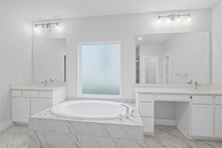 This primary bathroom is definitely move-in ready! Featuring a separate garden tub for soaking after a long day with custom tile detailing, white stained cabinets with countertops, spacious walk-in closet with shelving, high ceilings, custom paint, sleek and dark modern finishes.