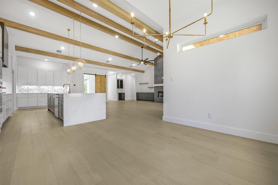 Kitchen with a barn door, a chandelier, light wood-style floors, a spacious island, and backsplash
