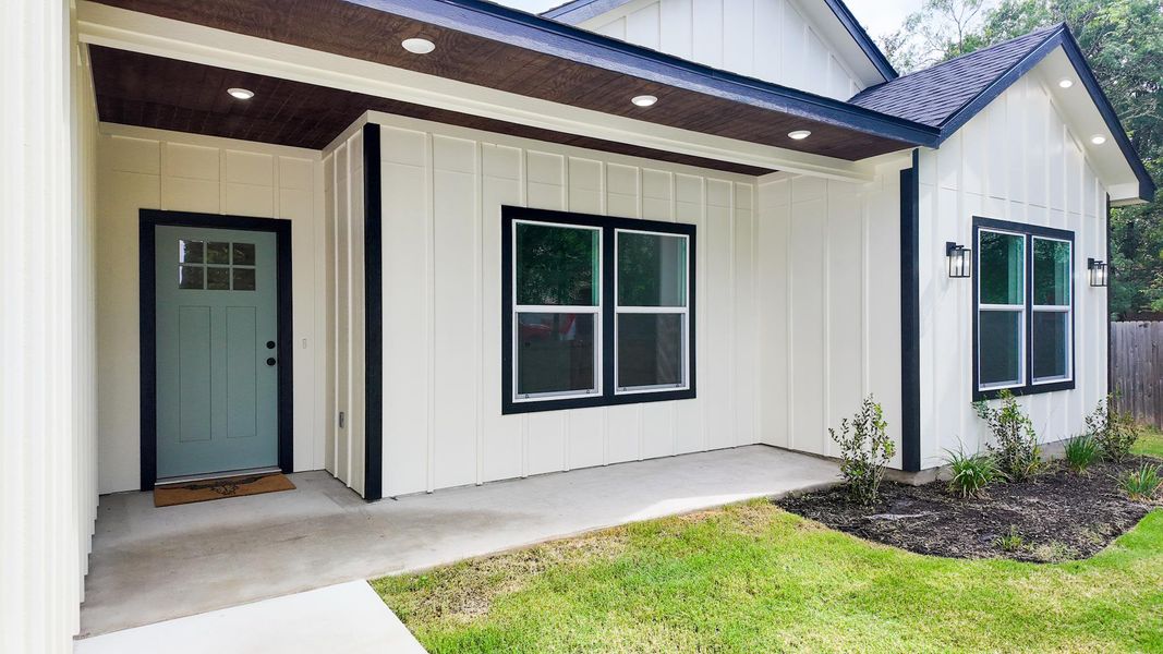 A striking exterior features board and batten siding, modern black trim, and an inviting covered porch.