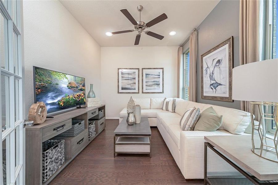 Spacious living area featuring dark wood-finish flooring, a contemporary ceiling fan, and recessed lighting