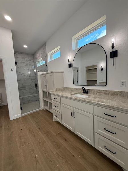 Bathroom featuring a marble finish shower, vanity, dark wood-type flooring, and a closet
