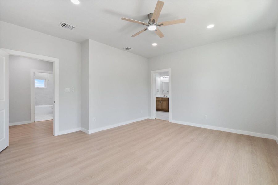 A spacious room offers comfortable living with light-toned flooring and an elegant ceiling fan for ultimate comfort.