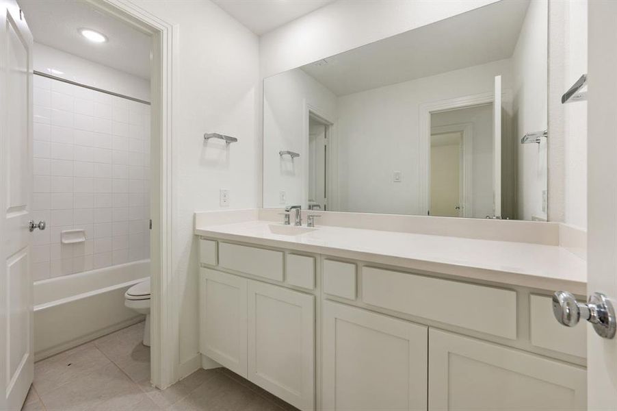 Bathroom featuring vanity, shower / bath combination, light tile patterned floors, and recessed lighting