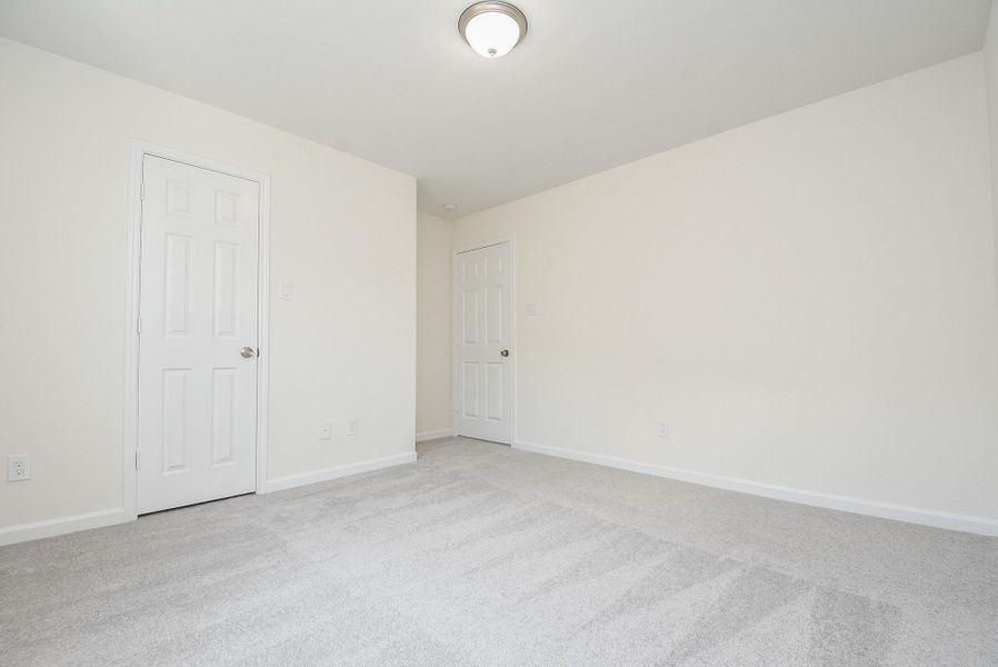 Empty room with carpet, two closed white doors, and a ceiling light fixture. Empty room with carpet, two closed white doors, and a ceiling light fixture.