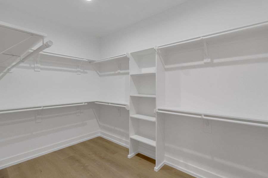 Generous walk-in closet with built-in shelving and ample hanging space. Generous walk-in closet with built-in shelving and ample hanging space.