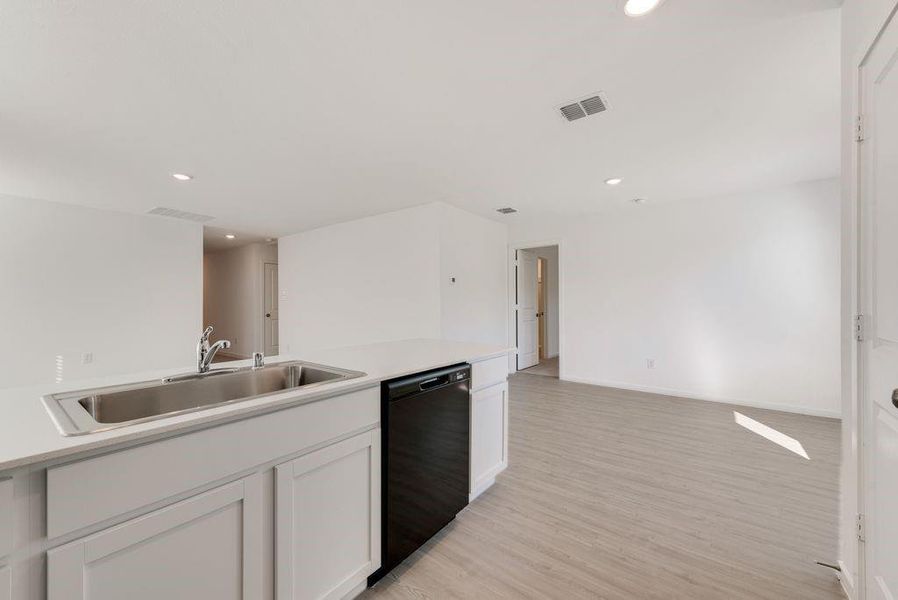 Kitchen featuring light hardwood / wood-style floors, black dishwasher, sink, and white cabinets