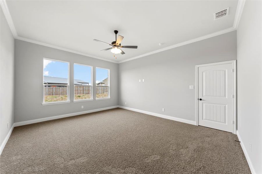 Carpeted empty room featuring ceiling fan and crown molding