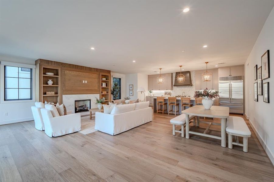 Living area with recessed lighting, light wood-style flooring, and a premium fireplace Living area with recessed lighting, light wood-style flooring, and a premium fireplace