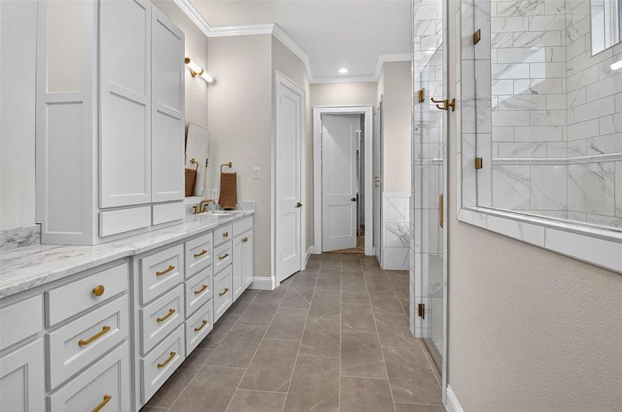Bathroom with a tile shower, double vanity, ornamental molding, light tile patterned floors, and recessed lighting