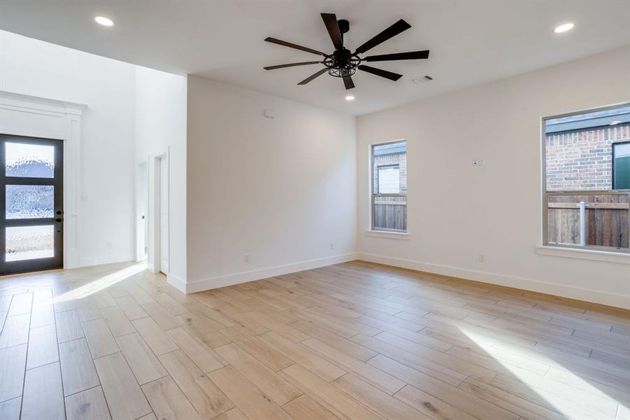 Unfurnished room with light wood-style floors, a ceiling fan, healthy amount of natural light, and recessed lighting