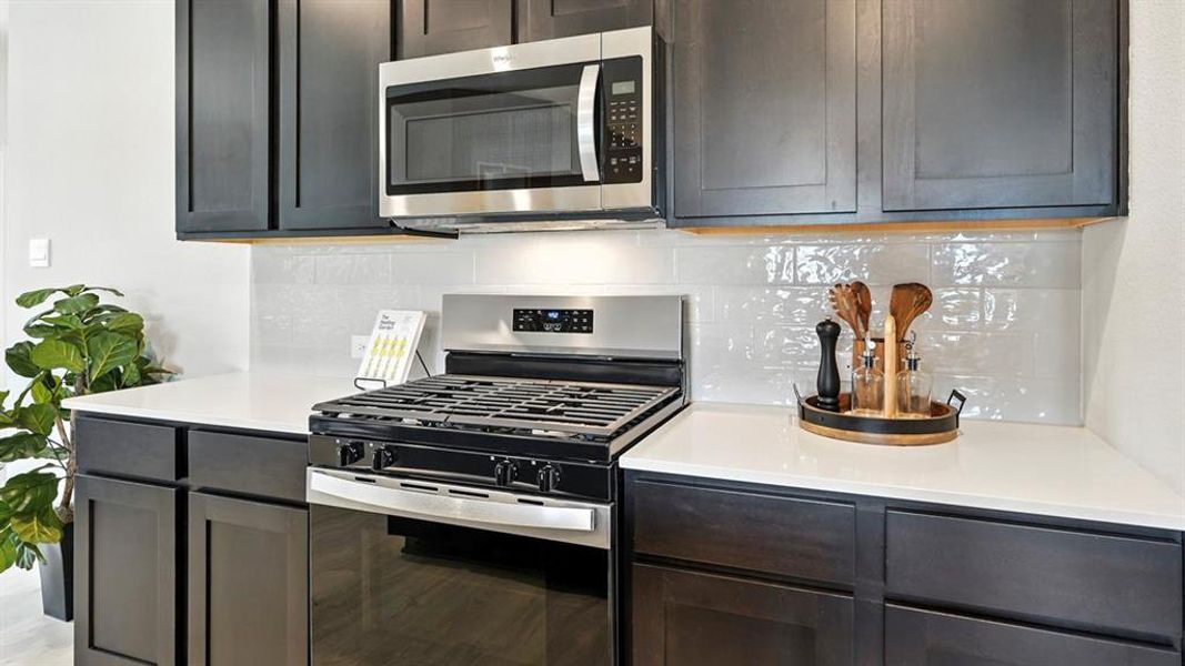 Kitchen featuring decorative backsplash, stainless steel appliances, and light stone countertops