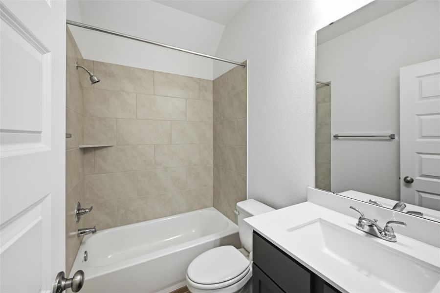 Modern bathroom featuring a sleek vanity with a polished sink, a cozy bathtub with elegant tile surround, and ample natural light.