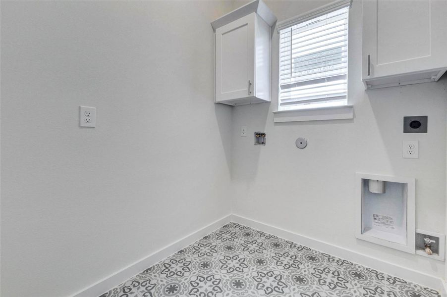 The laundry room features patterned tile flooring, upper cabinetry, a window with blinds, and dedicated washer and dryer connections. The bright white walls and added storage create a clean, functional space designed to keep laundry tasks organized while adding a stylish touch with the decorative floor detail. The laundry room features patterned tile flooring, upper cabinetry, a window with blinds, and dedicated washer and dryer connections. The bright white walls and added storage create a clean, functional space designed to keep laundry tasks organized while adding a stylish touch with the decorative floor detail.