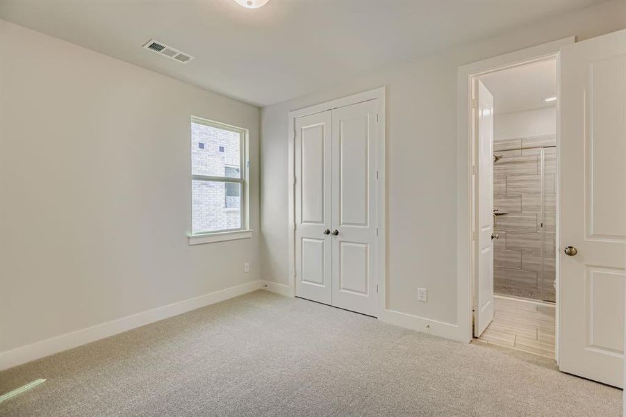 Unfurnished bedroom with ensuite bathroom, light carpet, and a closet