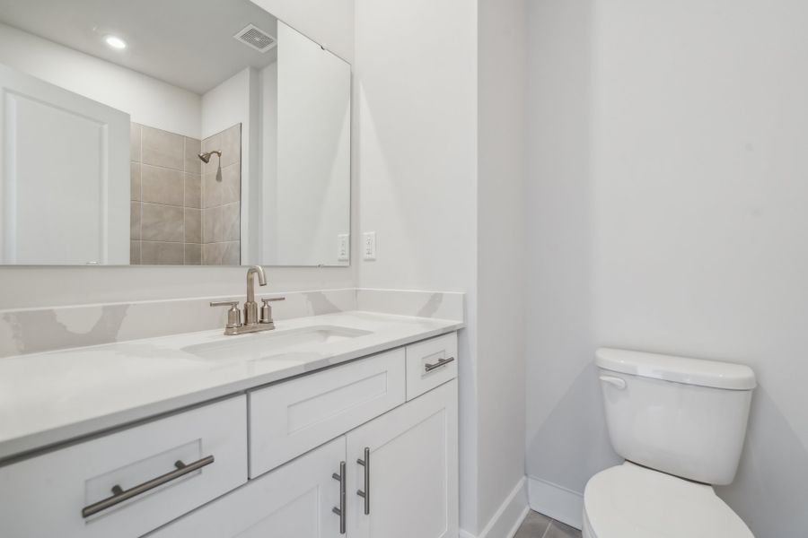 A bathroom with a sink toilet and mirror.
