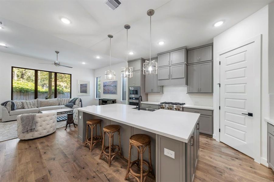 Step into the modern, chef’s dream kitchen, featuring an oversized island with bar seating, elegant pendant lighting, and sleek cabinetry that combines style with functionality.