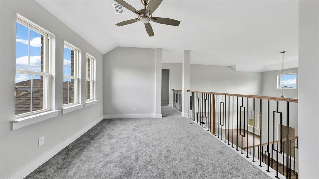 Carpeted spare room with ceiling fan and lofted ceiling