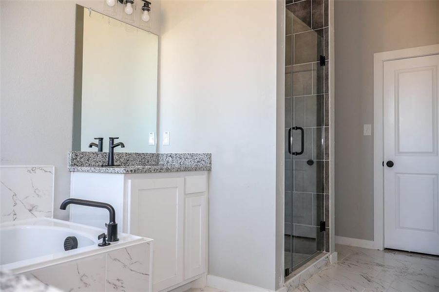 Full bathroom featuring marble look tiles, a stall shower, a bath, and vanity