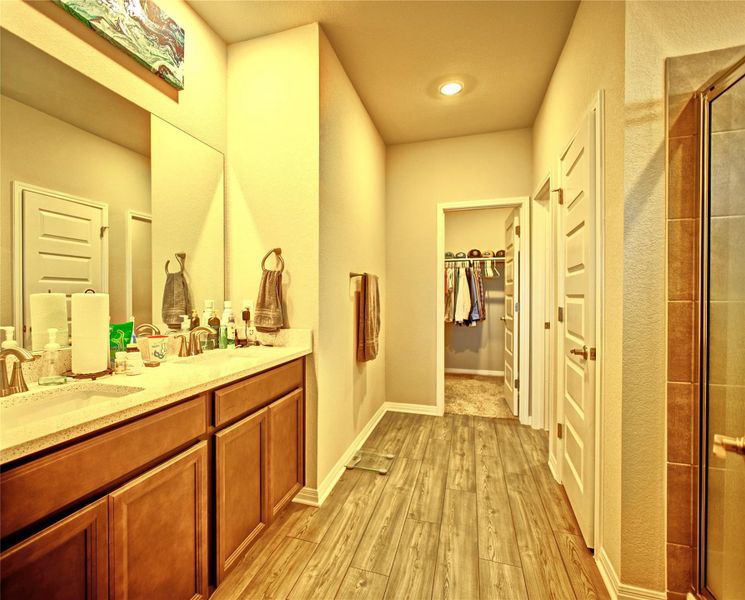 Full bathroom featuring a spacious closet, light wood-style flooring, double vanity, and a shower stall Full bathroom featuring a spacious closet, light wood-style flooring, double vanity, and a shower stall