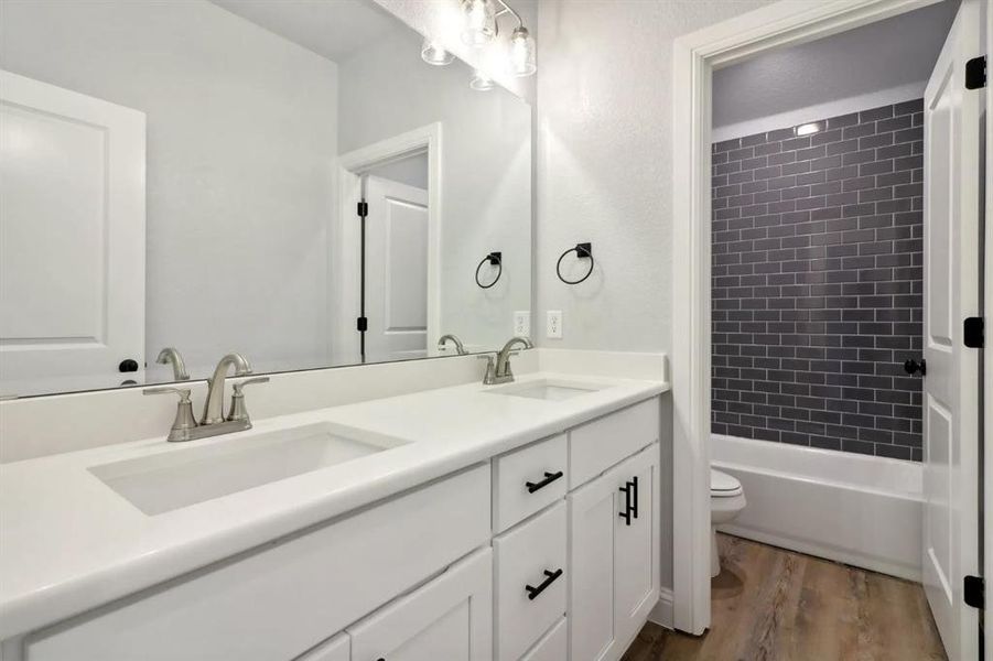 Full bathroom featuring vanity, hardwood / wood-style flooring, toilet, and tiled shower / bath combo