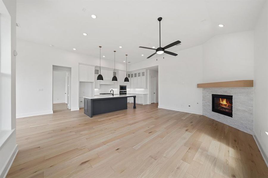 Unfurnished living room with recessed lighting, a fireplace, light wood-style flooring, and a ceiling fan Unfurnished living room with recessed lighting, a fireplace, light wood-style flooring, and a ceiling fan