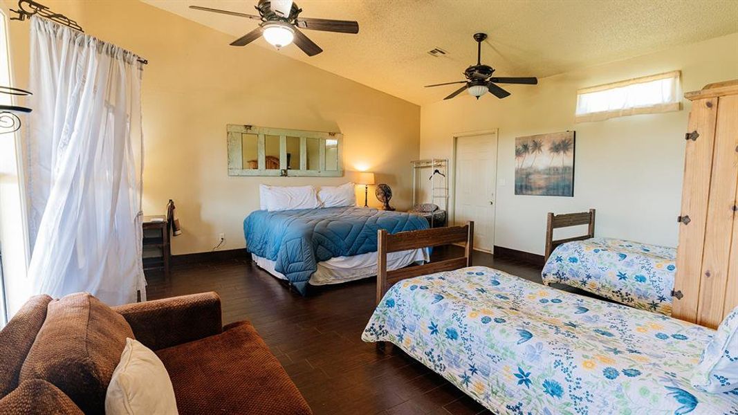 Bedroom featuring a textured ceiling, dark wood-style flooring, ceiling fan, a closet, and high vaulted ceiling