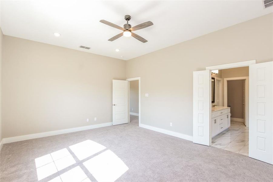 Unfurnished bedroom featuring ensuite bath and light carpet