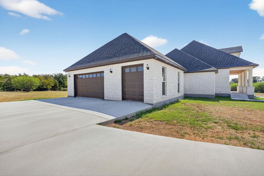 View of property exterior featuring roof with shingles, a yard, concrete driveway, and a garage View of property exterior featuring roof with shingles, a yard, concrete driveway, and a garage
