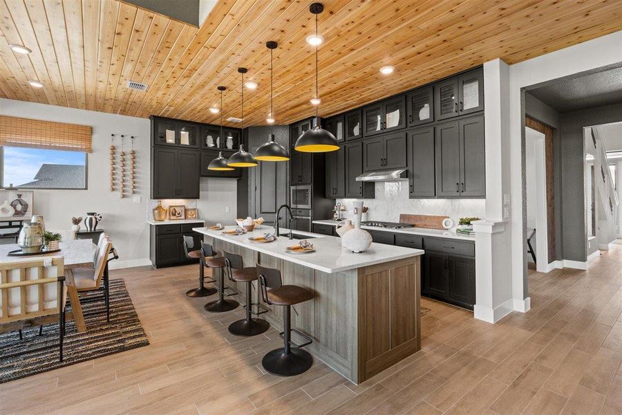 Kitchen with a kitchen breakfast bar, wooden ceiling, glass insert cabinets, an island with sink, and hanging light fixtures