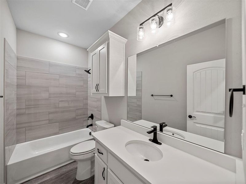 Full bathroom with vanity, bathtub / shower combination, and dark wood-style floors Full bathroom with vanity, bathtub / shower combination, and dark wood-style floors