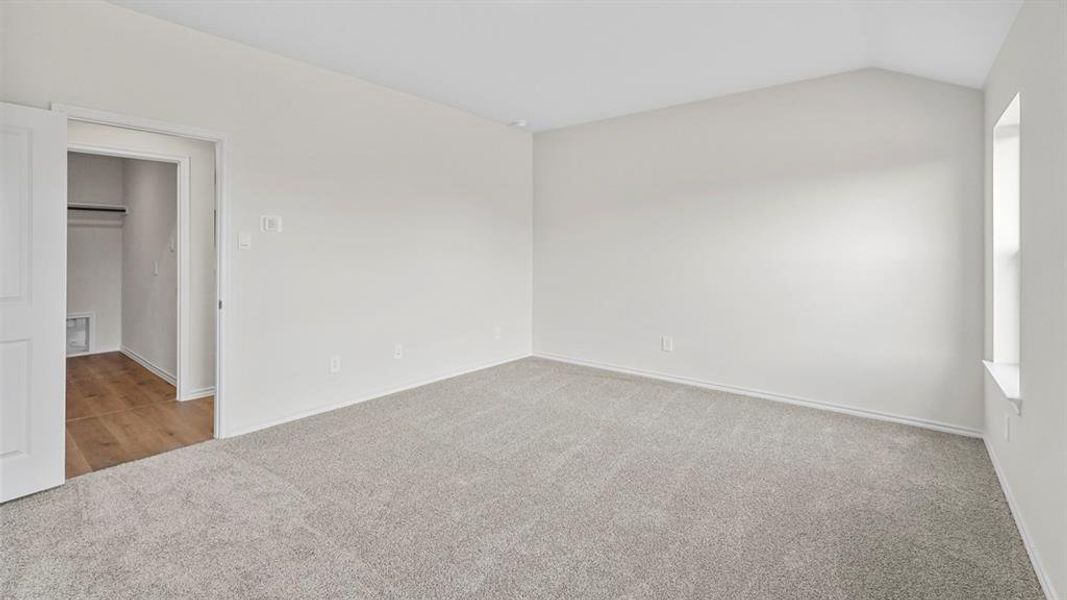 Unfurnished bedroom featuring light colored carpet and vaulted ceiling