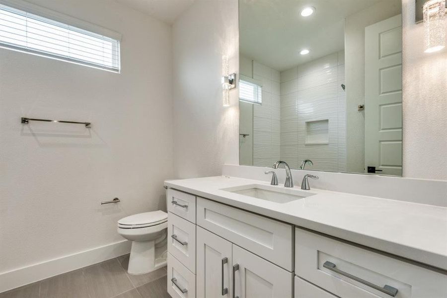 Bathroom with tiled shower, vanity, and toilet