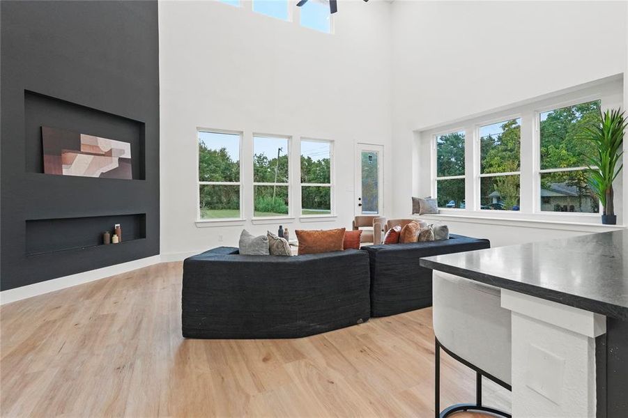Living area with light wood-style floors, a towering ceiling, and built in features Living area with light wood-style floors, a towering ceiling, and built in features