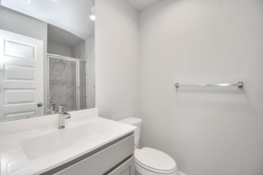 Secondary bath features tile flooring, a walk-in shower with tile surround, light stained wood cabinets, beautiful light countertop. Secondary bath features tile flooring, a walk-in shower with tile surround, light stained wood cabinets, beautiful light countertop.