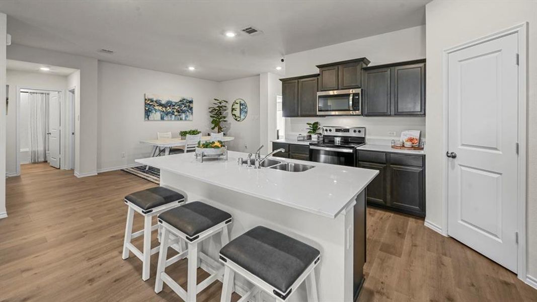 Kitchen featuring stainless steel appliances, a breakfast bar area, a kitchen island with sink, light wood finished floors, and recessed lighting