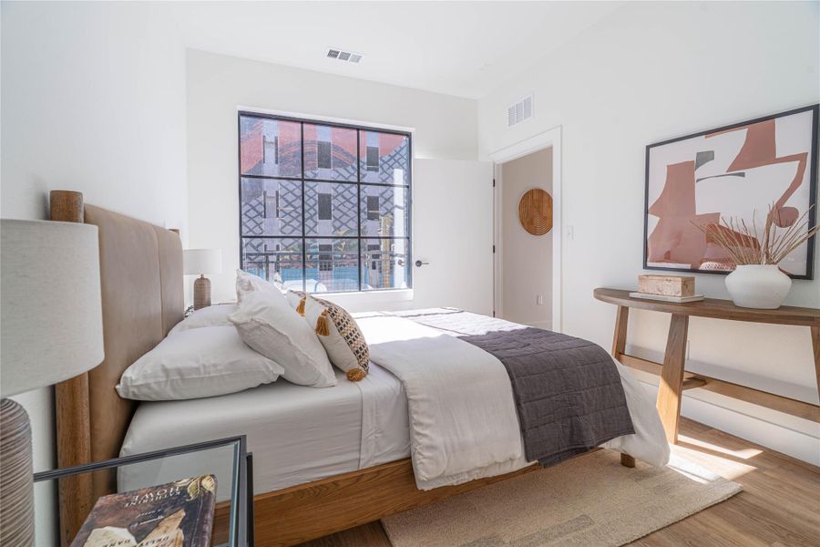 Bedroom featuring wood finished floors.Photos shown are of a model residence and are representative in nature. Actual residence may differ in layout, finishes, and views.