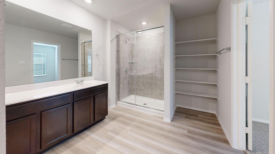 A naturally illuminated bathroom with wood flooring and a spacious walk-in shower.