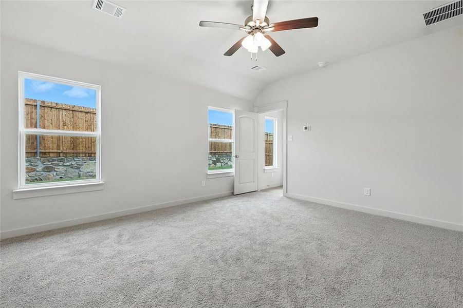 Carpeted empty room with ceiling fan and vaulted ceiling