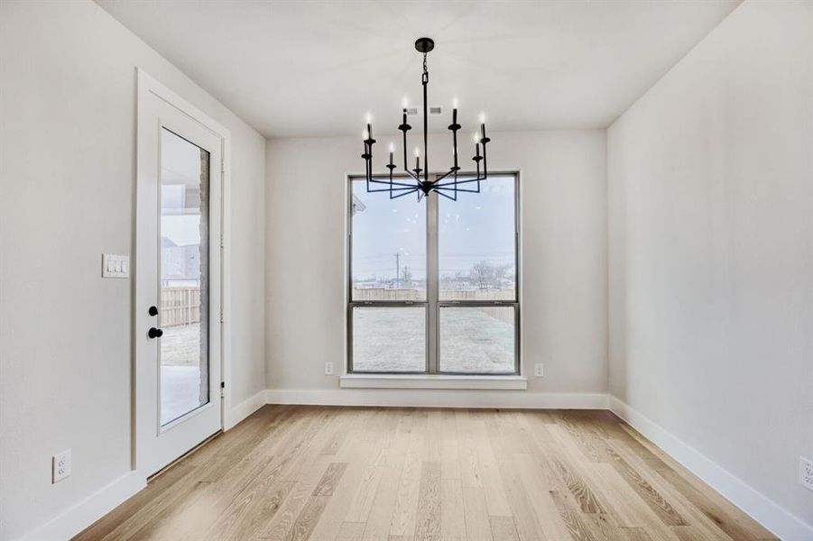 Unfurnished dining area with light wood-style floors and suspended lighting