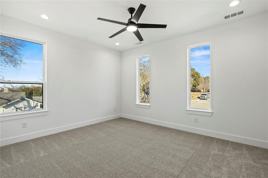 Spare room featuring light colored carpet, ceiling fan, recessed lighting, and healthy amount of natural light