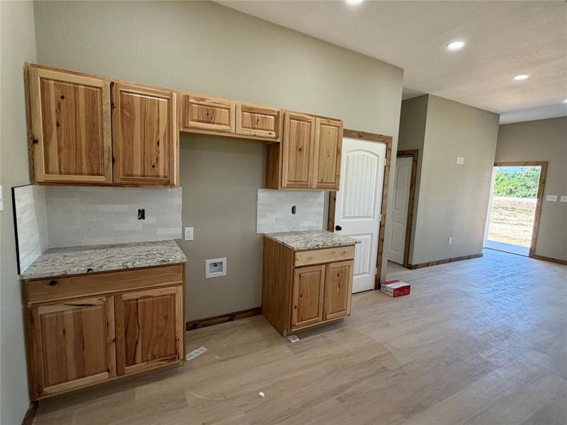 Kitchen area featuring natural wood cabinetry, light-toned countertops, and a subway tile backsplash