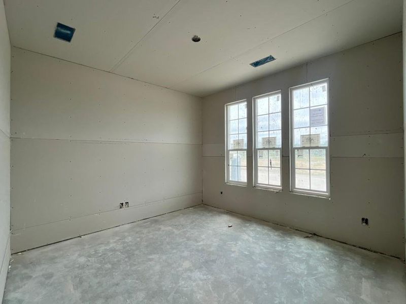 Room with three vertical windows, unfinished drywall, and a concrete subfloor